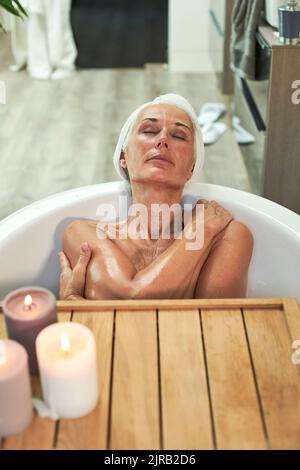 Reife Frau, die sich im Bad baden und entspannen kann Stockfoto