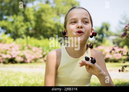 Nettes Mädchen essen Kirschen im Park Stockfoto