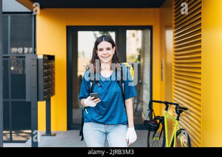 Glückliche junge Entbindung Frau mit Handy vor der Tür stehen Stockfoto