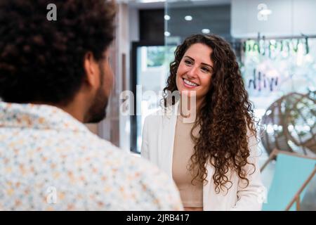 Lächelnde Brünette Geschäftsfrau, die Kollegen im Büro ansieht Stockfoto