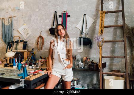 Durchdachte Modedesignerin, die in der Werkstatt mit der Hand in der Tasche steht Stockfoto