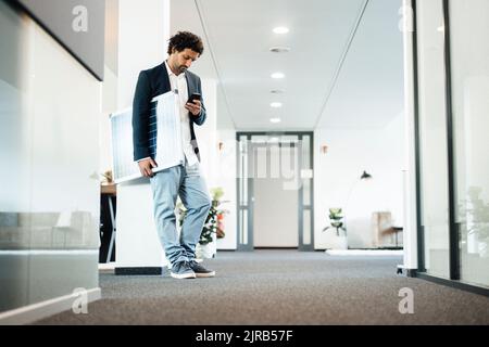 Geschäftsmann mit Solarpanel und Smartphone im Büro Stockfoto