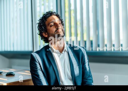 Geschäftsmann mit geschlossenen Augen im Büro Stockfoto