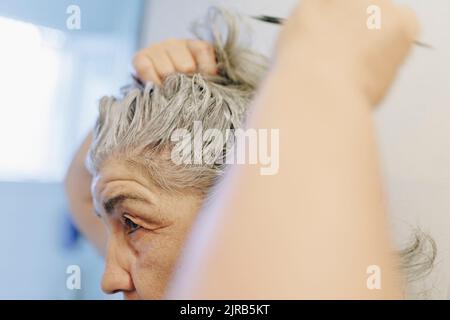 Ältere Frau, die zu Hause Haarfärbemittel anwendet Stockfoto