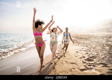 Unbeschwerte multirassische Freunde, die am Strand am Ufer genießen Stockfoto