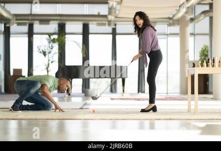 Geschäftsfrau spielt Golf von schockierten Geschäftsmann Stockfoto