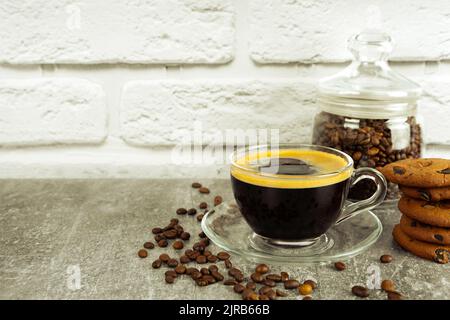 Schwarzer Kaffee Espresso in einem Glas mit Creme und Marmeladenglas in einem Glas. Kaffeebohnen auf grauer und weißer Ziegelwand mit Kopierfläche Stockfoto