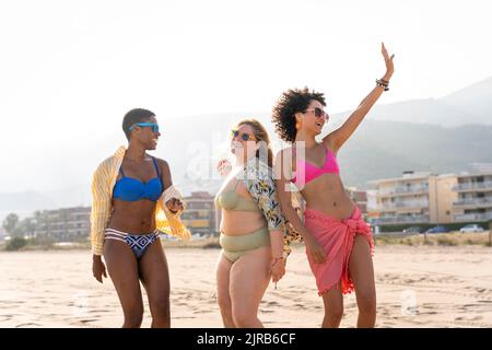Multirassische Freunde, die im Urlaub am Strand zusammen tanzen Stockfoto