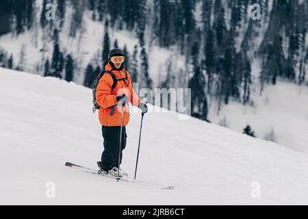 Skifahrer mit Helm und Brille, die auf Schnee steht Stockfoto