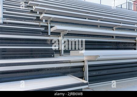 Nahaufnahme leerer Metallstadionbleacher-Sitze entlang des Ganges mit Stufen. Stockfoto