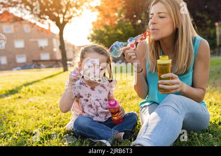 Mutter und Tochter blasen Blasen im Park Stockfoto