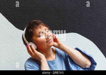 Entspannte Frau mit geschlossenen Augen, die mit Kopfhörern Musik hört Stockfoto