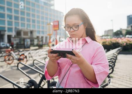 Teenager-Mädchen mit Down-Syndrom spielen Videospiel auf Smartphone Stockfoto