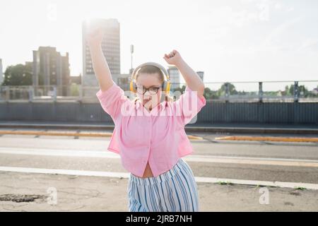 Teenager-Mädchen mit Kopfhörern, die Musik hören und auf der Straße tanzen Stockfoto