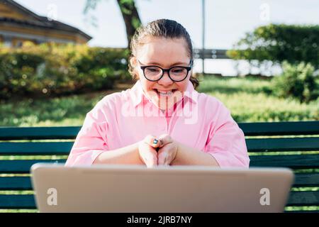 Glückliches Teenager-Mädchen mit Down-Syndrom auf Videoanruf über Laptop Stockfoto