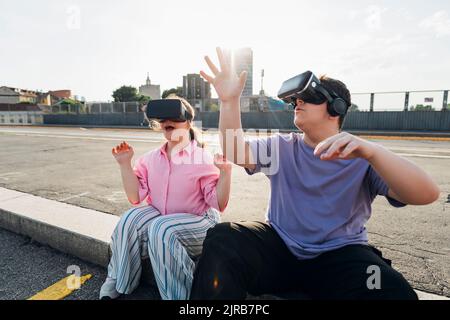 Mädchen und Junge im Teenageralter tragen VR-Brille auf der Stadtstraße Stockfoto