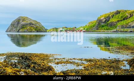 Norwegen, Nordland, Nusfjord, Küste der Insel Flakstadoya mit kleinem Fischerdorf im Hintergrund Stockfoto