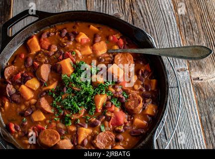 Chorizo-Wursteintopf mit Süßkartoffeln, Bohnen und Gemüse in einer gusseisernen Pfanne Stockfoto