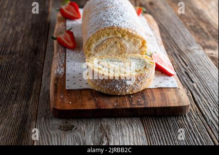 Hausgemachte schweizer Rolle mit Schlagsahne isoliert auf Holztisch. Vorderansicht Stockfoto