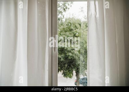 Regentropfen auf dem Fenster durch Glas gesehen Stockfoto