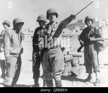 Ein Vintage-Foto um den 1943. Juli von General George Smith Patton Junior, das während der alliierten Invasion Siziliens mit amerikanischen Soldaten posiert, trägt den Codenamen Operation Husky während des Zweiten Weltkriegs Stockfoto