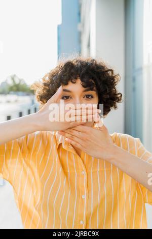 Junge Frau mit Händen den Mund Stockfoto