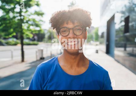 Glücklicher junger Mann, der an einem sonnigen Tag eine Brille trägt Stockfoto