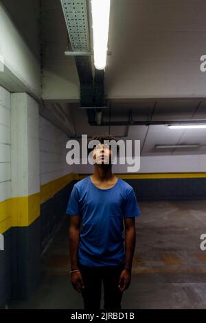Junger Mann, der auf das LED-Licht im unterirdischen Gang schaut Stockfoto