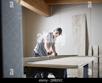 Fliesenleger, der Klebstoff auf die Fliese auf der Baustelle aufgibt Stockfoto