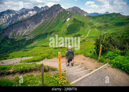 Ältere Frau, die auf Treppen in den Bergen Fellhorn und Kanzelwand, Allgau, Bayern, Oberstdorf, Deutschland, geht Stockfoto