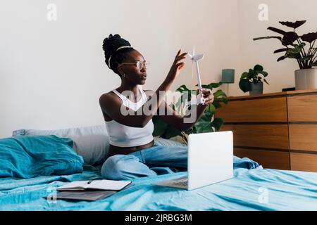 Geschäftsfrau, die zu Hause das Windenergieanlagenmodell mit Laptop analysiert Stockfoto