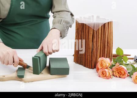 Florist bei der Arbeit: Wie man Blumenarrangement mit Rosen und Zimtstangen machen. Schritt für Schritt, Tutorial. Stockfoto