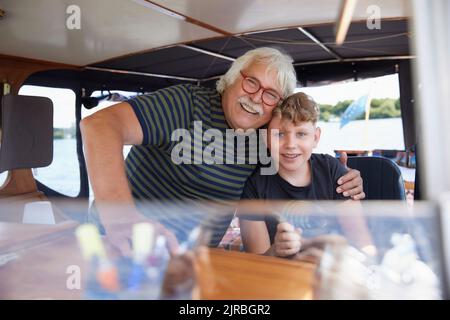 Glücklicher Großvater umarmt Enkel im Boot Stockfoto