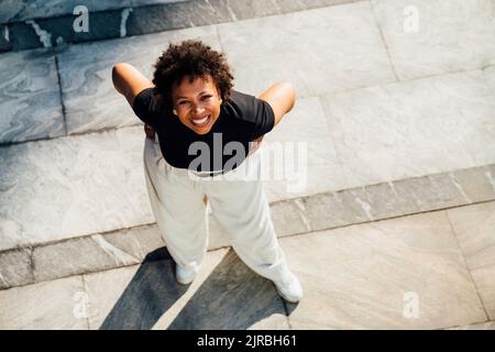 Glückliche junge Geschäftsfrau, die mit den Händen auf den Hüften steht Stockfoto