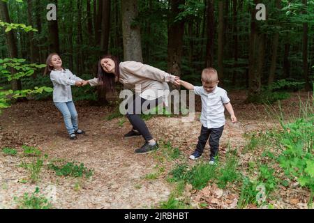 Kinder ziehen Mutter Spaß im Wald Stockfoto