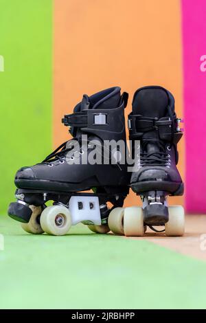 Rollschuhe auf dem Boden vor der mehrfarbigen Wand Stockfoto