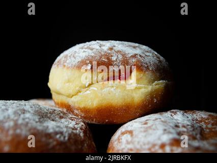 Polnische pączki frittierte Donuts. Fat Donnerstag, Tłusty czwartek Fest, traditioneller Tag in Polen. Pączek Essen, gefüllt mit Hagebuttenmarmelade. Stockfoto