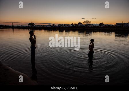 Junge Jungen kühlen sich am Fluvia-Fluss ab, wenn die Sonne in Sant Pere Pescador, Provinz Girona, Spanien untergeht. Stockfoto