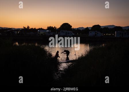 Ein Paar fischt am Ufer des Fluvia Flusses, als die Sonne in Sant Pere Pescador, Provinz Girona, Spanien untergeht. Stockfoto