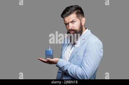 Parfüm oder köln Flasche und Parfümerie, Kosmetik, Duft köln Flasche, männlich Holding köln. Maskulines Parfüm, bärtiger Mann in einem Anzug. Maskulin Stockfoto