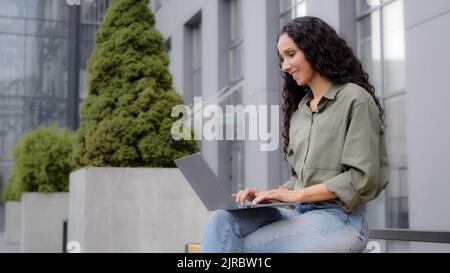 Frau Benutzer Journalist Schriftsteller Arbeiter freiberuflich sitzen auf Haufen in der Nähe von Stadtgebäude arbeiten mit Laptop Remote-Projekt Online-Geschäftsfrau Analyse Stockfoto