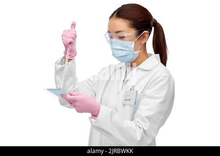 asiatische Wissenschaftlerin in Maske, die an Impfstoffen arbeitet Stockfoto