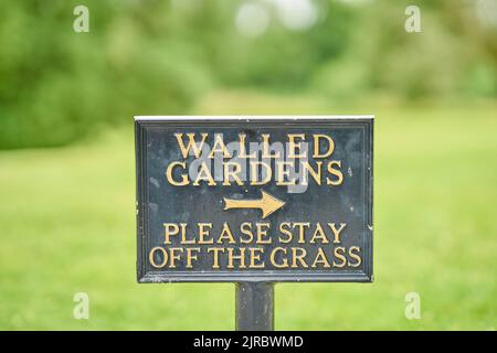 Ein Informationsschild, das höflich Menschen auffordert, vom Gras weg zu bleiben. Stockfoto