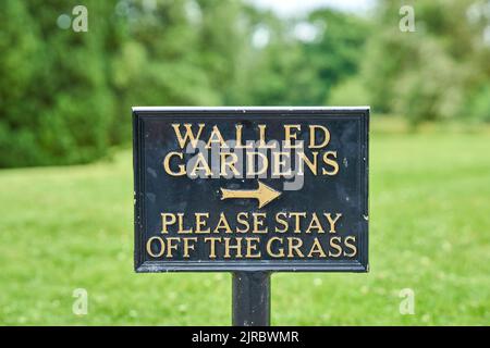 Ein Informationsschild, das höflich Menschen auffordert, vom Gras weg zu bleiben. Stockfoto