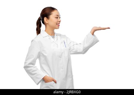 asiatische Ärztin hält etwas auf der Hand Stockfoto