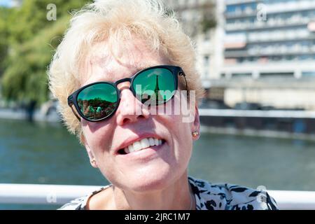 Als weibliche Touristin, die Paris besucht, blickt Frankreich auf den Eiffelturm. Das berühmte Wahrzeichen spiegelt sich in der Oakley-Brille der Frau wider Stockfoto