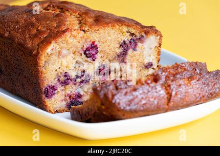 Ein frisch zubereiteter Brombeere-, Apfel- und Walnusskuchen. Der Kuchen wurde zu Hause vom Bäcker gemacht und wird in Scheiben geschnitten und zeigt die Früchte im Inneren des Kuchens Stockfoto