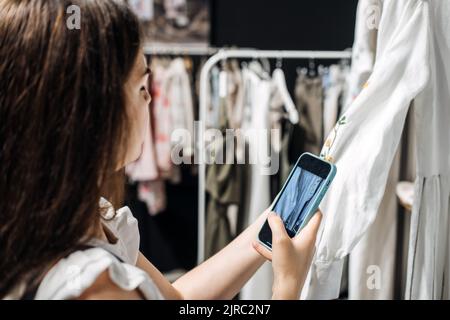 E-Commerce und Online-Verkauf. Frau, die im Laden Kleidung fotografiert. Second Hand, Verkauf von gebrauchter Kleidung. Stockfoto