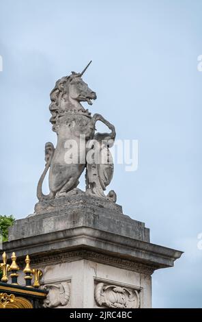 London, England, Großbritannien - 6. Juli 2022: Buckingham Palace. Nahaufnahme der grauen Einhorn-Statue aus Stein auf der Torsäule unter hellblauem Himmel. Einige goldene Str Stockfoto