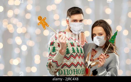 Paar in medizinischen Masken und weihnachtspullover Stockfoto